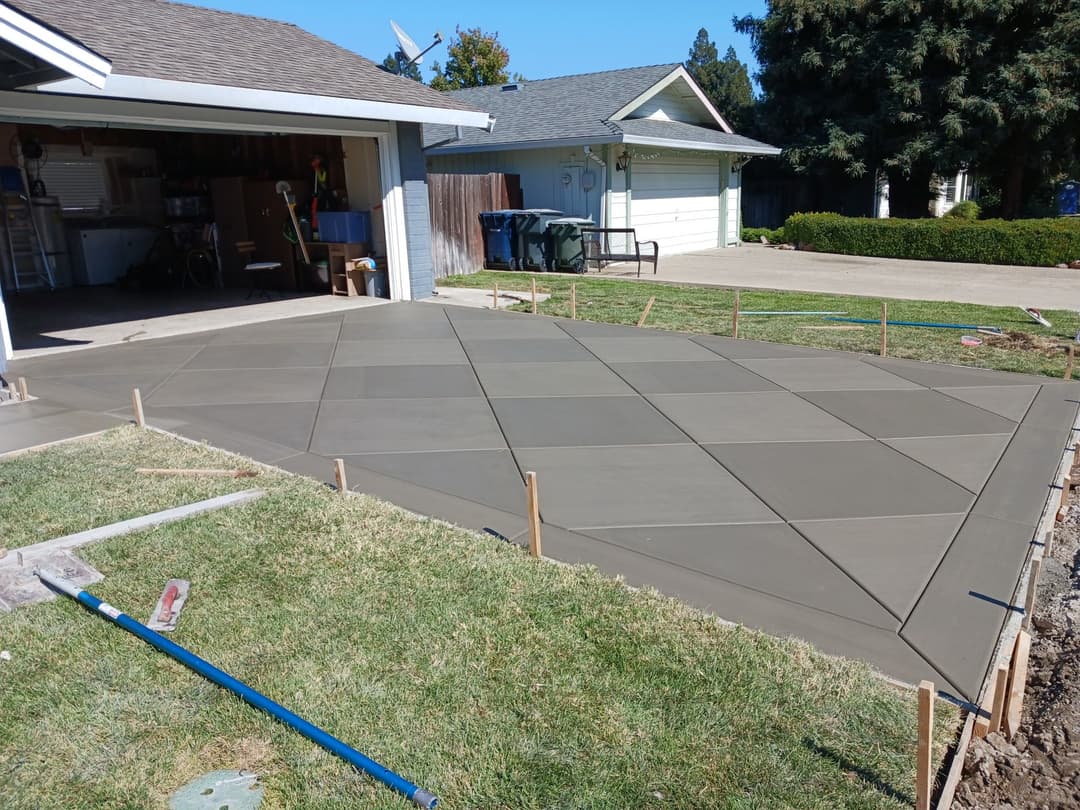 Freshly poured decorative concrete driveway with a geometric pattern beside a garage.